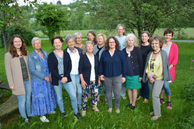 14 Teammitglieder auf einer Wiese stehend und dahinter Bäume